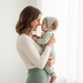 Mother and baby wearing matching cream and sage green coordinating outfits